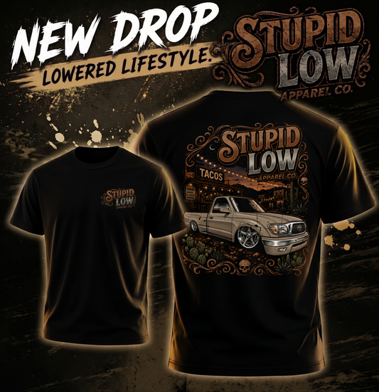 Two black graphic T-shirts shown on a dark promotional background. The left shirt shows a small chest print reading 'Stupid Low Apparel Co.